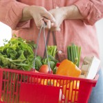 Midsection of mature man carrying basket full of vegetables at home